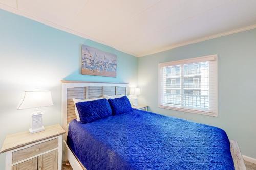 大洋城Assateague House 306的一间卧室设有蓝色的床和窗户。