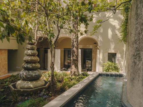 赫罗纳Hotel Palau Fugit的一座树木繁茂的房屋内,设有一座带喷泉的游泳池