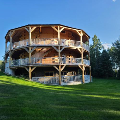MarlboroSundance Country Lodge B&B的一座大型木制建筑,在绿色的田野上设有阳台