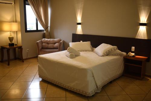 卡拉济纽Hotel Plaza Sul的卧室配有床、椅子和灯