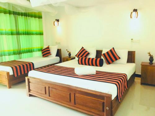 锡吉里亚锡吉里亚拉纳欣格自然别墅的一间卧室配有两张床和条纹枕头