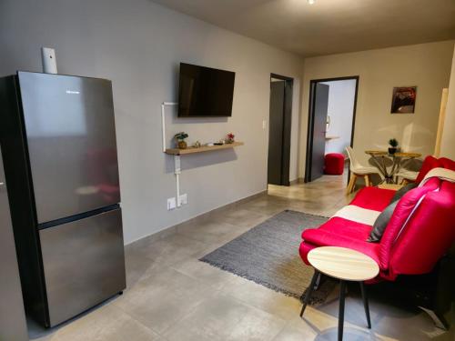 比勒陀利亚Circa Aparthotel - 1 Bedroom Apartment - close to Menlyn的客厅配有红色椅子和冰箱