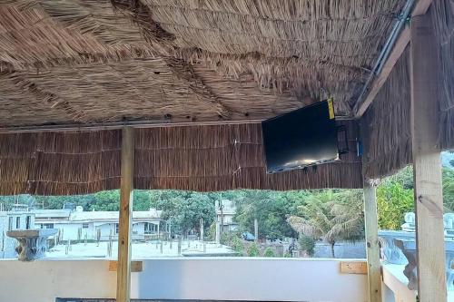 海地角KING vacation Home的茅草屋顶上的平面电视