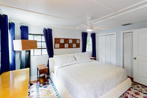 塔维涅Turquoise Turtle Manor的卧室配有白色的床和蓝色窗帘