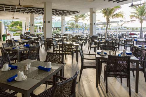 马霍礁圣淘沙集团马霍海滩全包度假村赌场酒店及Spa的一间空餐厅,配有桌椅,并种植了棕榈树