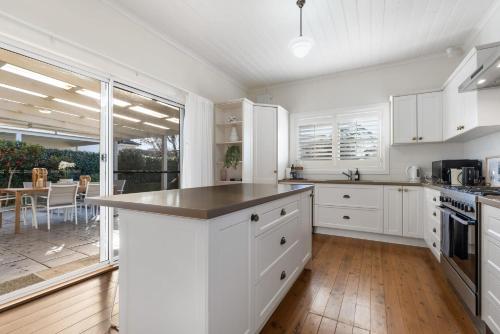奥兰治Sampson Cottage - Historic Charm的一间厨房,配有白色的橱柜和大窗户