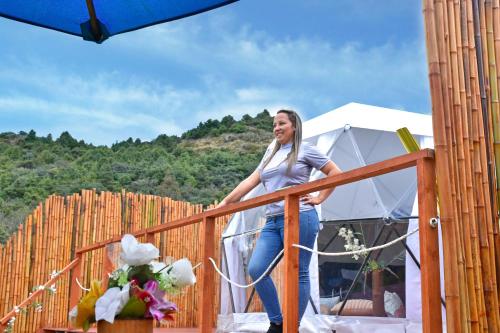 瓜塔维塔Glamping Claro de Luna的站在帐篷旁边的木制阳台上的女人