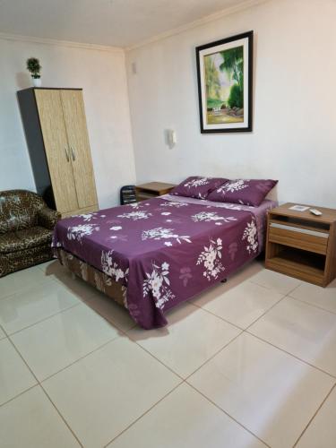 伊瓜苏港Pacurí Hotel的一间卧室配有一张紫色的床和一张桌子