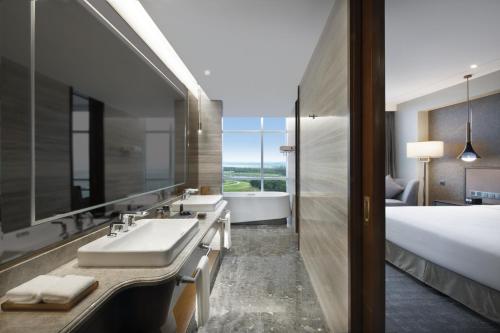 青岛青岛国际机场君廷酒店的一间带水槽和浴缸的浴室以及一张床