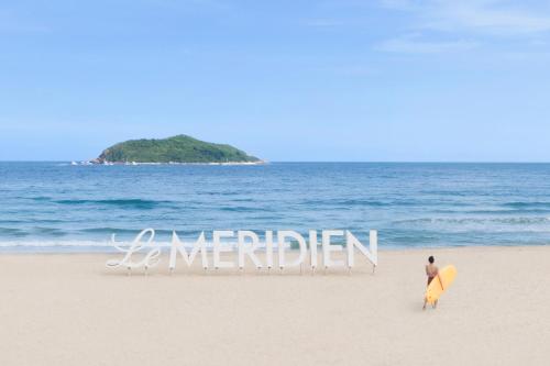 万宁石梅湾艾美度假酒店（三亚机场穿梭巴士+每日免费亲子活动）的站在海滩上的人,有冲浪板