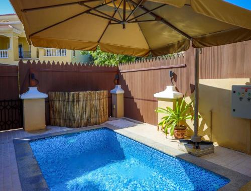 拉斯阿尔卡麦Dar 66 Plunge Pool Resort Townhouses的一个带遮阳伞的游泳池,位于围栏旁