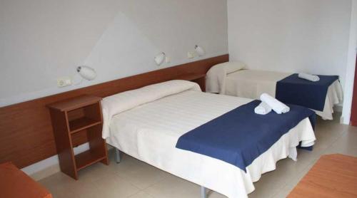 兰卡Residencia Sant Jordi Llança的酒店客房设有两张床和一张桌子。