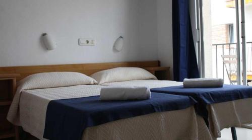 兰卡Residencia Sant Jordi Llança的一间卧室设有两张带蓝色床单的床和窗户。