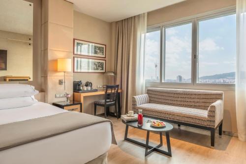 巴塞罗那Hesperia Barcelona Presidente的酒店客房配有床、沙发和桌子。