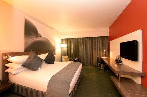 约翰内斯堡Southern Sun Rosebank的酒店客房配有一张床、一张书桌和一台电视。