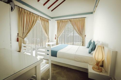帕西库达The Beach house by Kay Jay Hotels的一间白色卧室,配有床和2个窗户