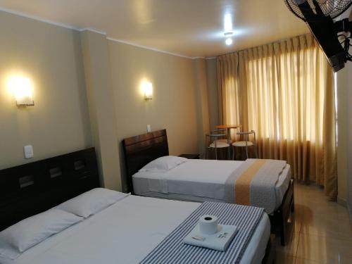 皮斯科HOSTAL LA NOCHE - Pisco的酒店客房设有两张床和一张桌子。