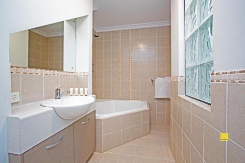 朱里恩湾The Pearl的浴室配有盥洗盆、镜子和浴缸