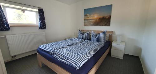 RambinFewo Steuerbord的一间卧室配有一张带蓝色和白色棉被的床