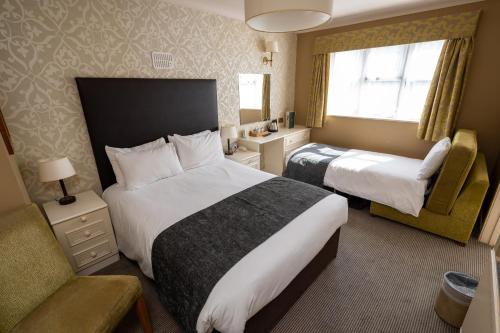 SibsonMillers Hotel by Greene King Inns的酒店客房,配有两张床和椅子