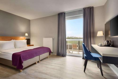 奥伯丁Ramada by Wyndham München Airport的配有一张床、一张书桌和一扇窗户的酒店客房