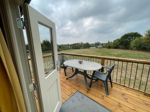 TodberBathsheba, Luxurious Shepherds Hut set in Todber a hamlet set in Thomas Hardy's iconic rural Dorset的甲板上配有桌椅的门廊