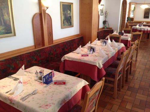 巴特塔茨曼斯多夫Hotel zum Kastell的餐厅的一排桌子,有红色桌布