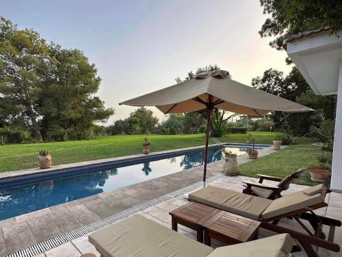 塔巴卡Villa avec piscine privée的游泳池旁的遮阳伞和椅子