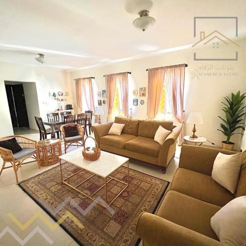阿卜杜勒国王经济城بِيُوتات الرفآه - ڤيلا الواحة 2的客厅配有沙发和桌子
