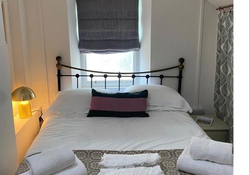 圣贾斯特Charming Studio in Heart of Vibrant St Just, West Cornwall的一间卧室配有一张带白色床单的床和一扇窗户。