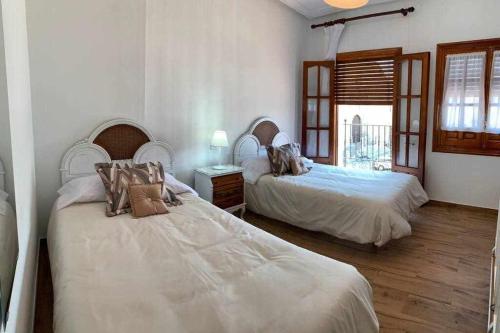La Puebla de MontalbánEl Balcón de La Rosa的配有白色墙壁和木地板的客房内的两张床