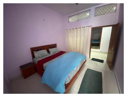 巴德里纳特Badrinath Jb Laxmi hotel的一间卧室配有一张带蓝色床单的床和一扇窗户。