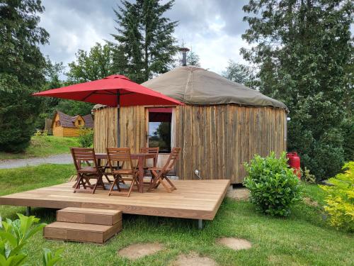 萨尔特-雷斯温泉les Refuges du Chalet的凉亭配有椅子和一张带红色遮阳伞的桌子