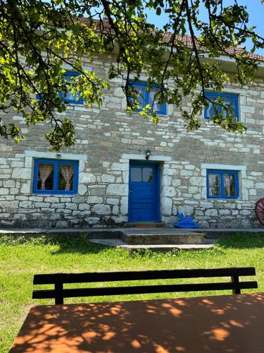 普列夫利亚Etno kuća Krvavac的一座石头建筑,设有蓝色的门和长凳