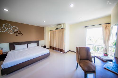 罗勇Phavina Hotel Rayong SHA Extra Plus的一间卧室配有一张床、一张桌子和一把椅子
