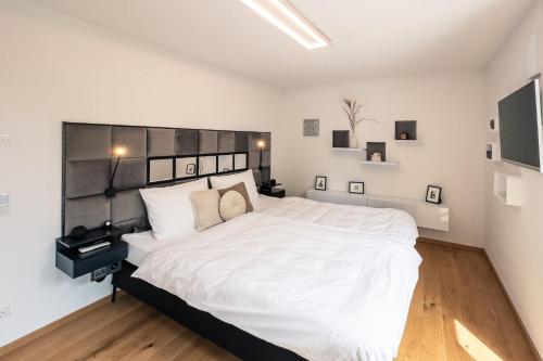 科尔贝尔莫尔CREST - Alpdeluxe - Balkon-Wanne-Tiefgarage-BBQ的卧室配有白色大床和白色墙壁