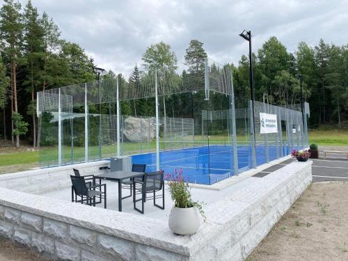 MellösaHoliday home Mellösa IV的游泳池旁的网球场配有桌椅