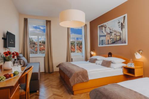 布拉格Hotel Merkur - Czech Leading Hotels的酒店客房设有一张床、一张书桌和两个窗户。