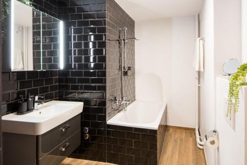 蒙特勒Marché 28 Guesthouse的黑色瓷砖浴室设有水槽和浴缸