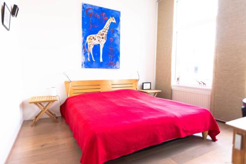 哈莱姆B&B Brouwersvaart的卧室配有红色的床,墙上挂着长颈鹿画