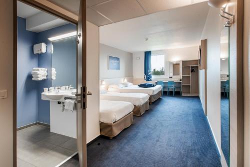 科尔讷巴里厄Ace Hôtel Toulouse Blagnac的酒店客房设有两张床和盥洗盆