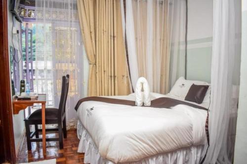 WebuyeGLAMOUR APOLLO HOTEL的一间卧室配有一张床、一张书桌和一个窗户。