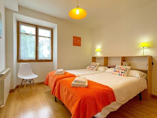 蓬特拉雷纳Apartamentos Puente La Reina的一间卧室配有一张带橙色毯子的大床