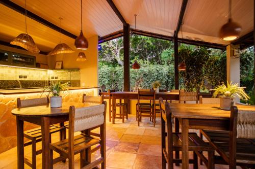 杰里科科拉Pousada Carioca - Pousada de Charme的餐厅设有木桌和椅子以及大窗户。
