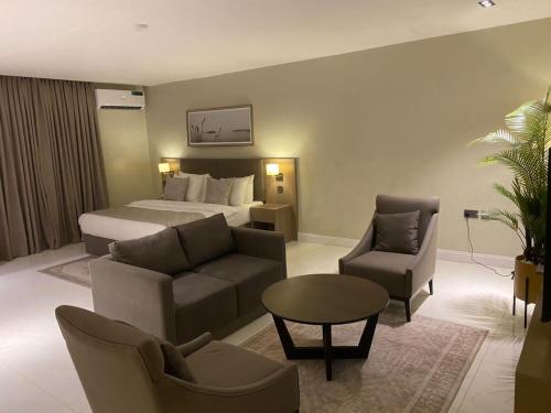 阿布贾Knightsbridge Hotel & Suites的酒店客房配有一张床、一张沙发和椅子。
