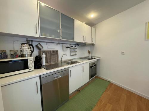 波尔图Burgães II Apartment的厨房配有白色橱柜和绿色地毯。