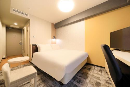 成田成田Richmond酒店的酒店客房设有一张白色大床和椅子