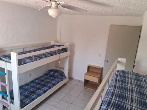 CoyucaCasa Laguna的一间卧室设有两张双层床和吊扇