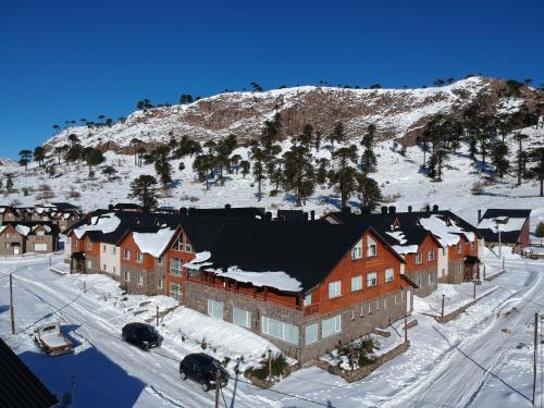 卡薇亚惠Villa Maihue departamentos de montaña - Caviahue的山边的大建筑,有雪