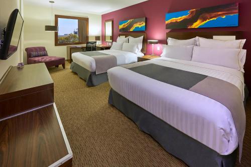 瓜达拉哈拉Holiday Inn Guadalajara Patria-Universidad, an IHG Hotel的酒店客房设有两张床和电视。